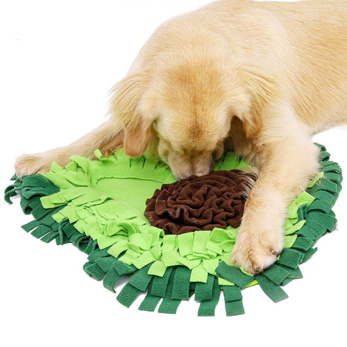 Avocado-shape snuffle mat — full product view with dog lying on side, showing the dense fleece petals and brown center "pit"
